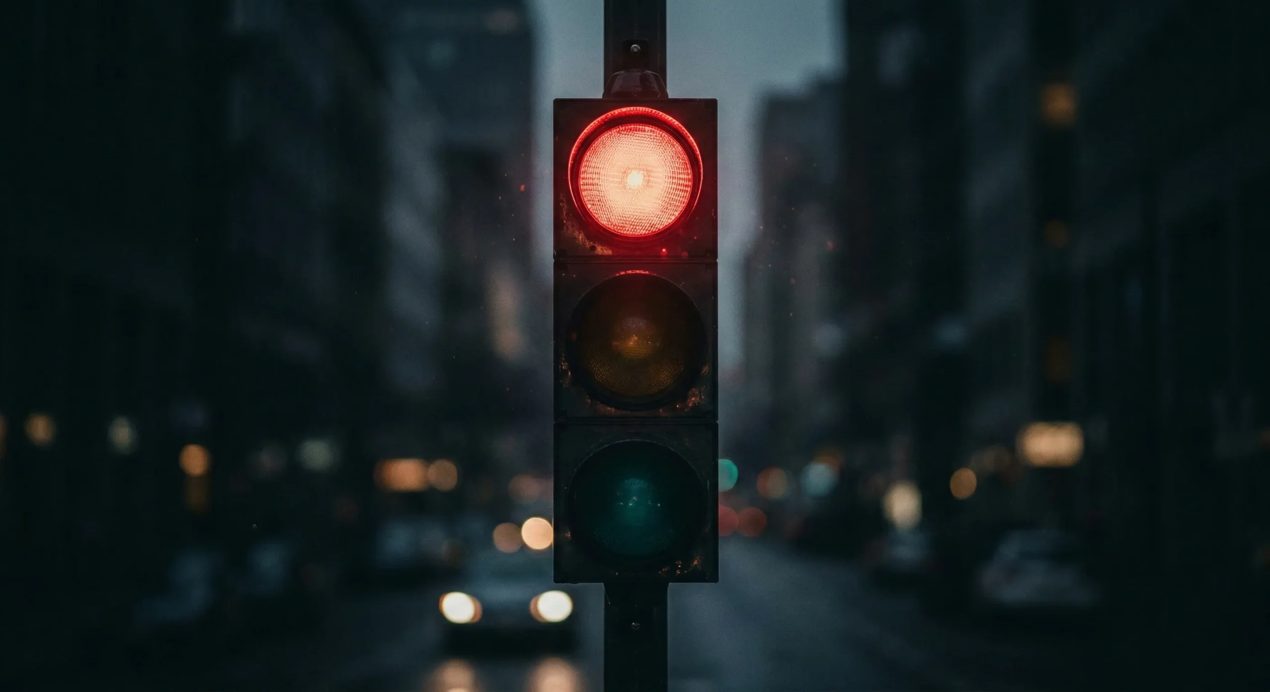 Traffic light with red light in sharp focus against dark blurred background - safeword system in BDSM romance