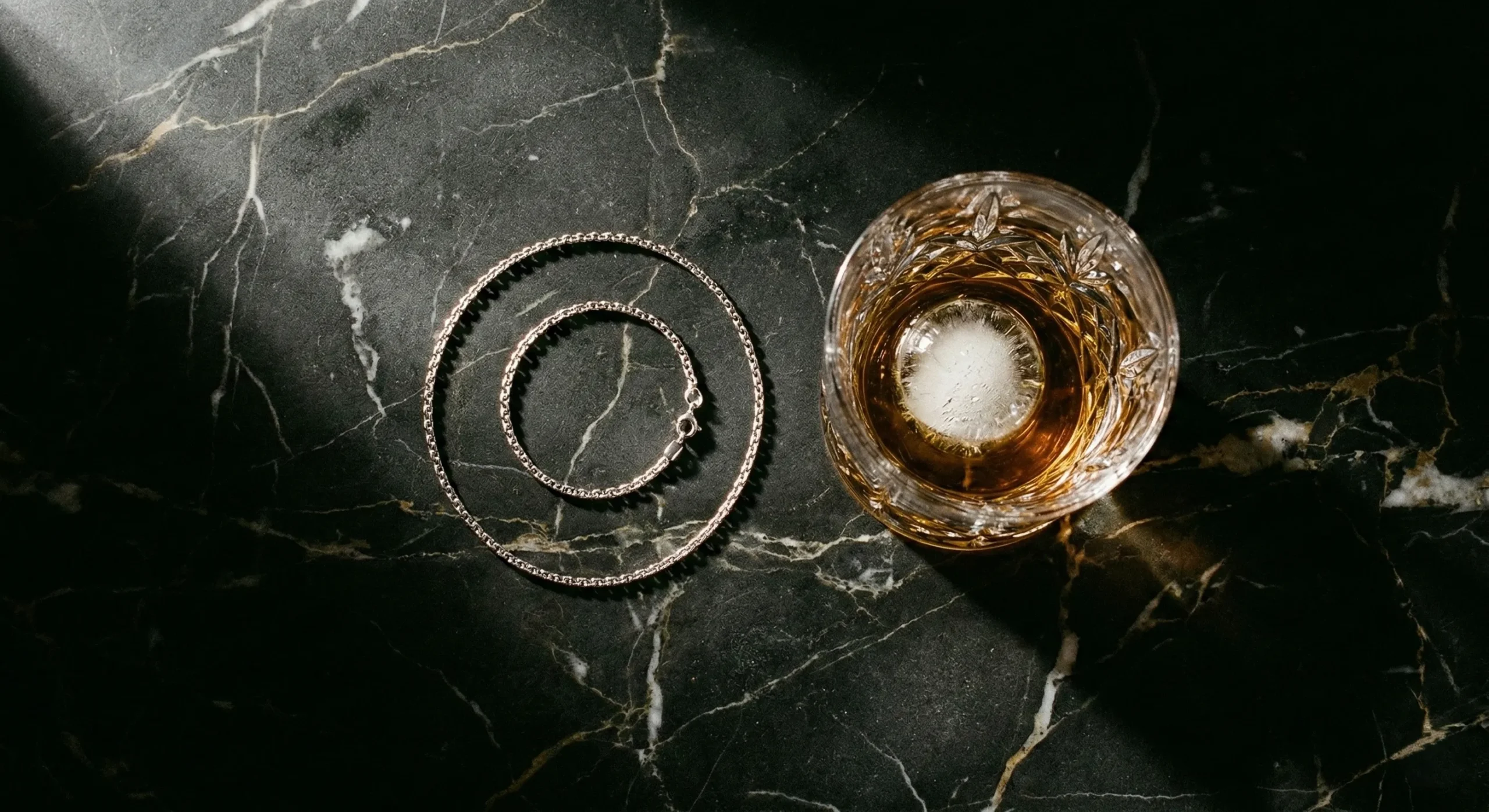 Dark romance section break — chain and whiskey luxury flat lay forbidden age gap
