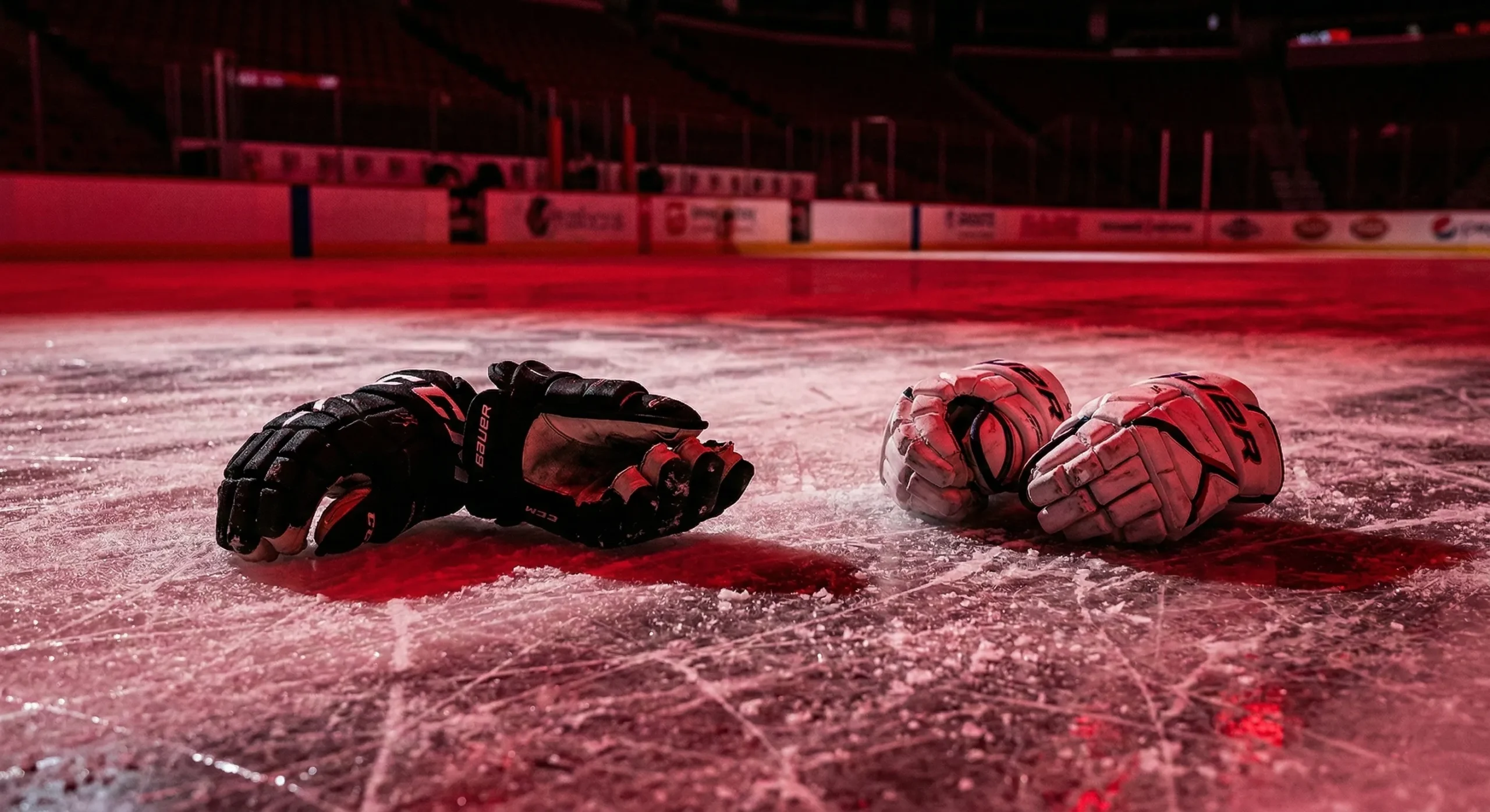 Two pairs of hockey gloves dropped on ice under red dramatic lighting - Puck Off by Jace Wilder enemies to lovers spotlight
