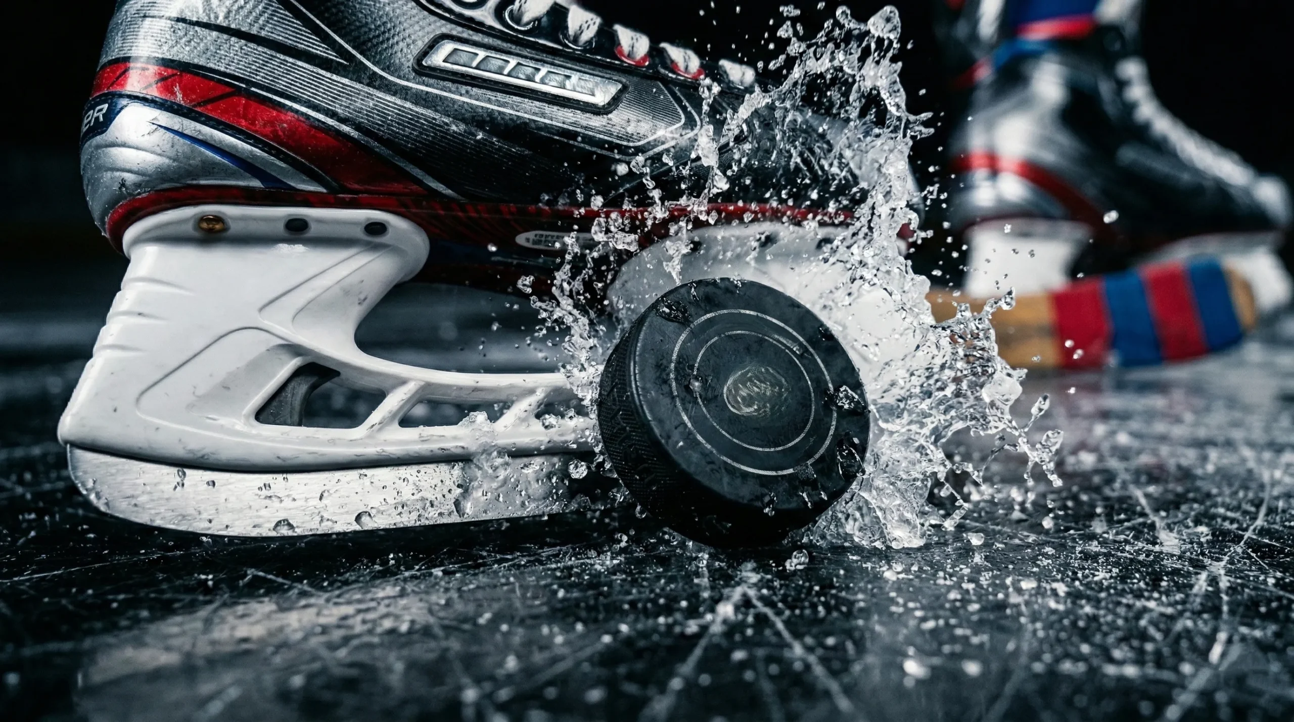 Hockey puck sitting on skate blade with frozen ice spray mid-action extreme close-up - what makes great hockey romance
