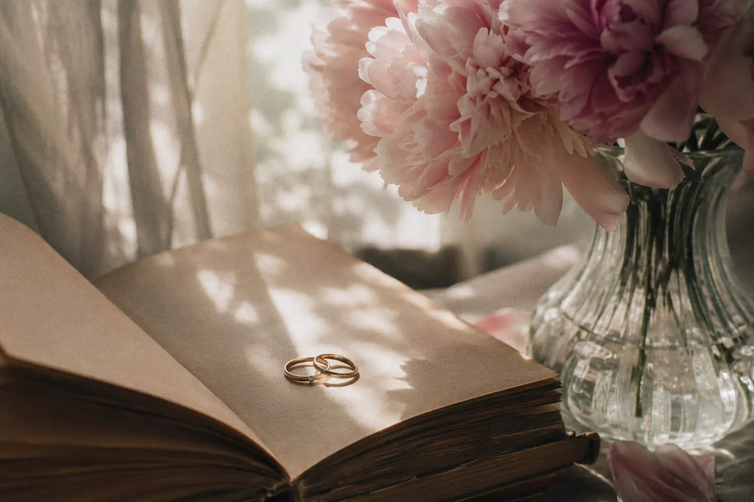 Two gold rings on an open poetry book beside pink peonies — sapphic FF friends to lovers romance